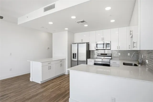 a kitchen with stainless steel appliances a stove top oven and white cabinets