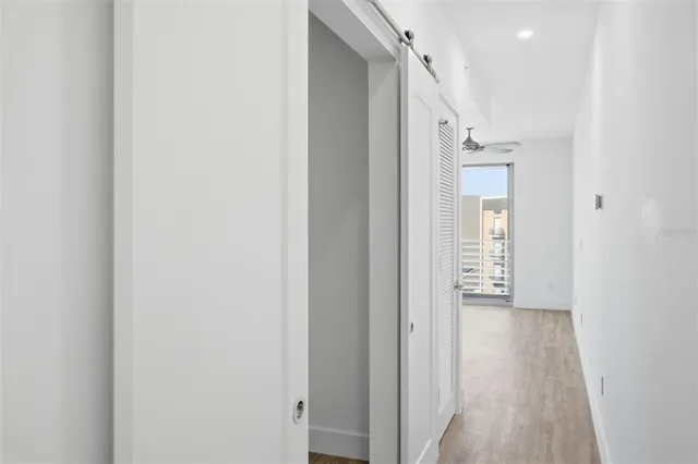 a view of an empty room with wooden floor and a bathroom