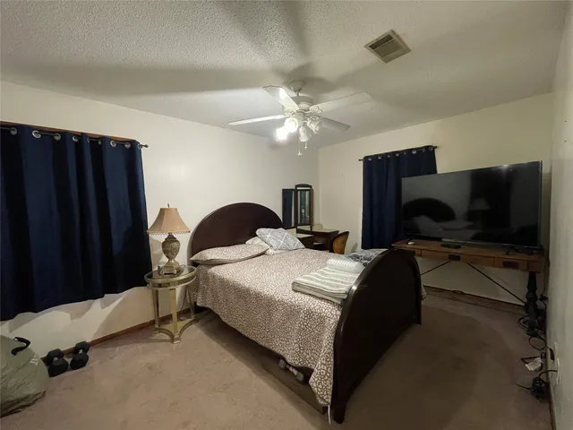 a bedroom with a bed and a flat tv screen on dresser
