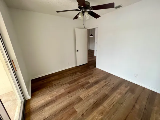 a view of empty room with wooden floor and fan