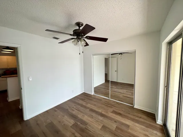 a view of empty room with wooden floor and fan