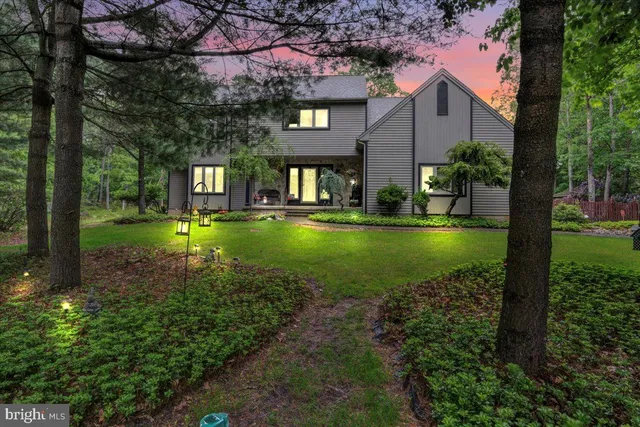 a view of a brick house with a yard and large trees