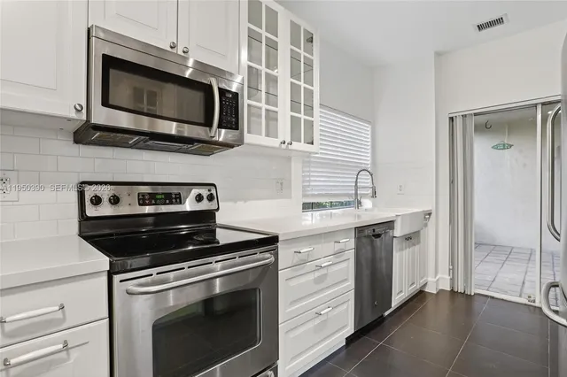 a kitchen with white cabinets and stainless steel appliances