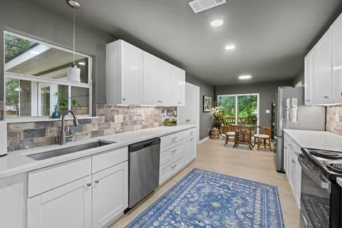 a large white kitchen with a sink and cabinets