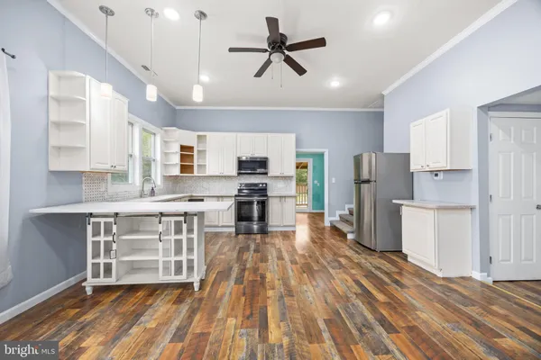 a kitchen with stainless steel appliances granite countertop a stove top oven a sink dishwasher a microwave oven and a refrigerator with wooden floor