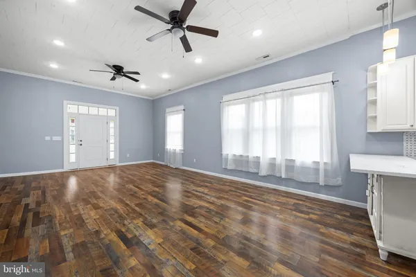 a view of empty room with wooden floor and ceiling fan