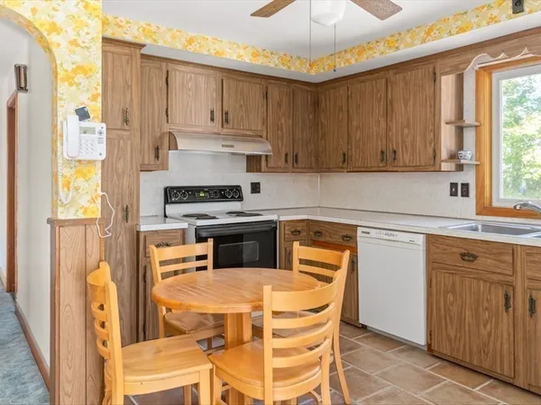 a kitchen with stainless steel appliances granite countertop a stove a sink dishwasher and a refrigerator with wooden cabinets