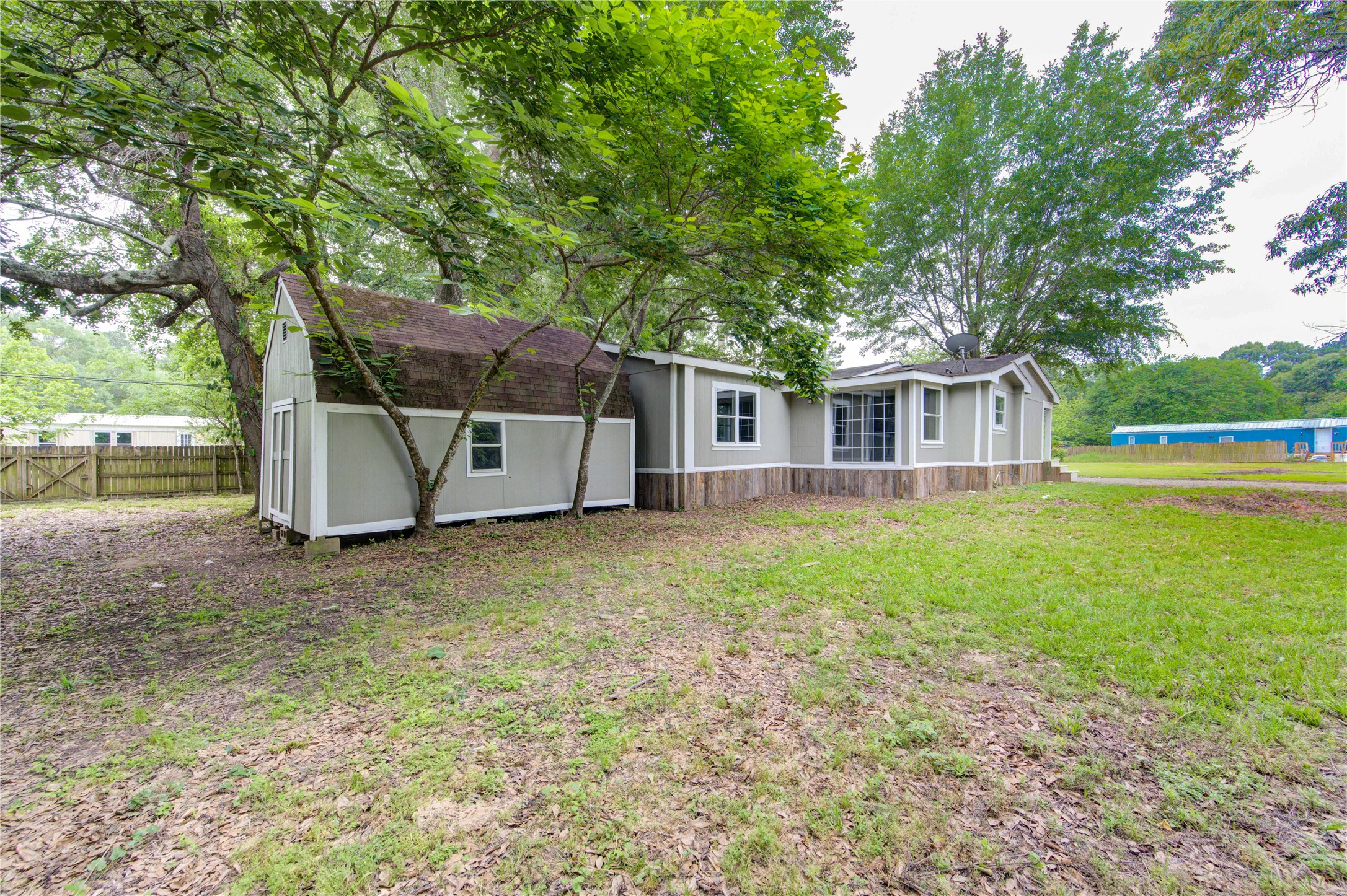 30226 Davis Street Magnolia, TX 77355 - Photo 44 of 50 Charming single-story home with a rustic exterior, nestled in a spacious yard with mature trees. The property features a large lawn area and a fenced perimeter, offering privacy and ample outdoor space. Ideal for those seeking a tranquil setting with room to enjoy nature.
