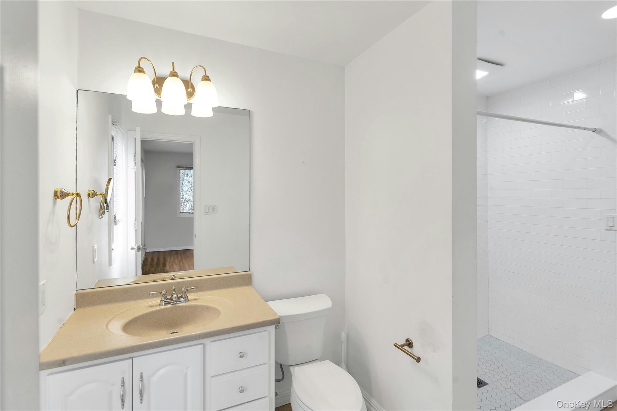 23 Bellows Terrace Hampton Bays, NY 11946 - Photo 17 of 31 a bathroom with a granite countertop sink a toilet a mirror and shower