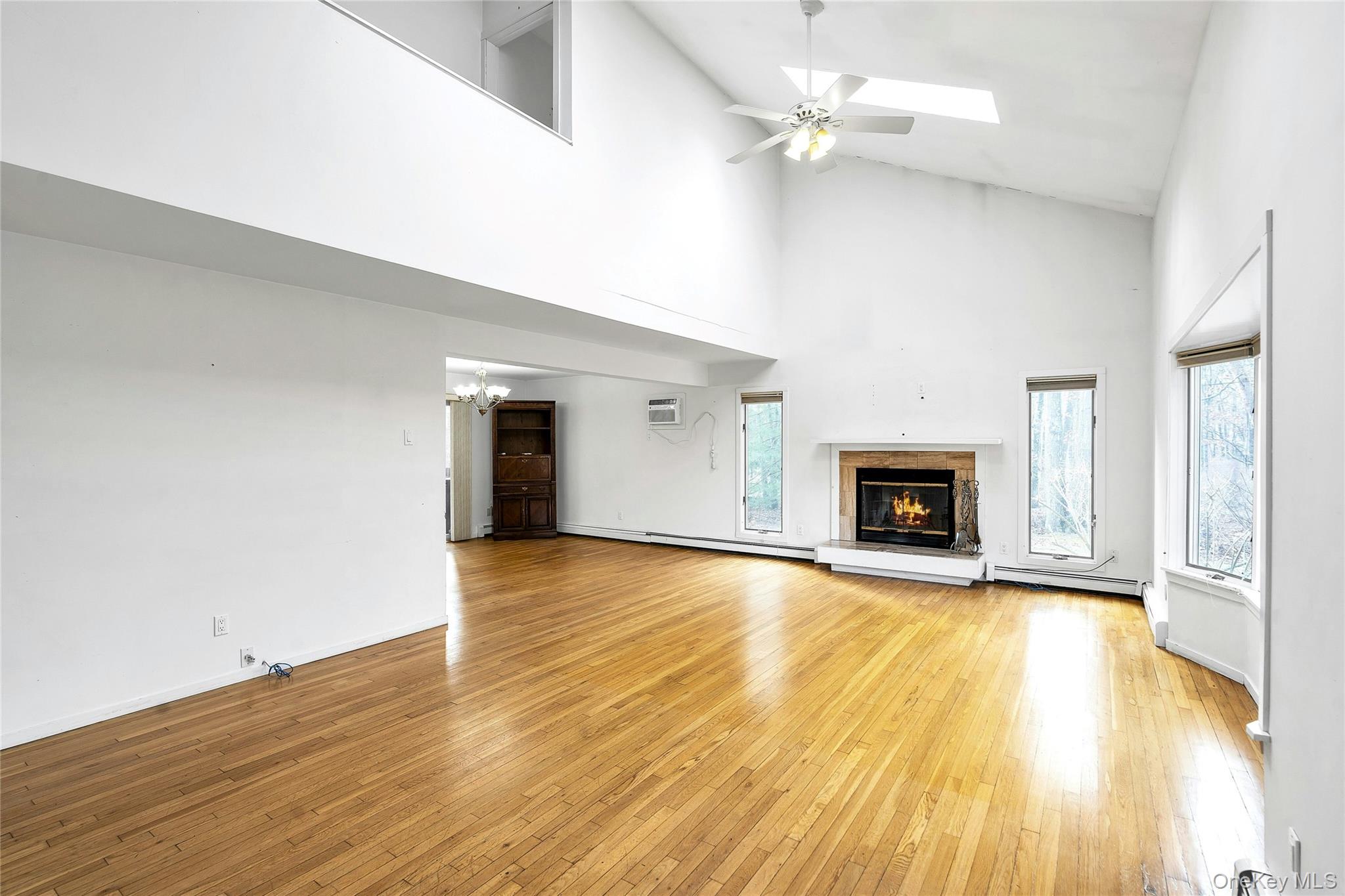 23 Bellows Terrace Hampton Bays, NY 11946 - Photo 5 of 31 an empty room with wooden floor fireplace and windows