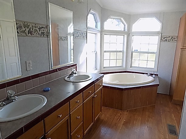 304 Tucker Road Lizella, GA 31052 - Photo 8 of 18 a bathroom with a double vanity sink a mirror and a bathtub next to a window