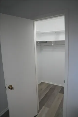 an empty room with wooden floor closet and windows