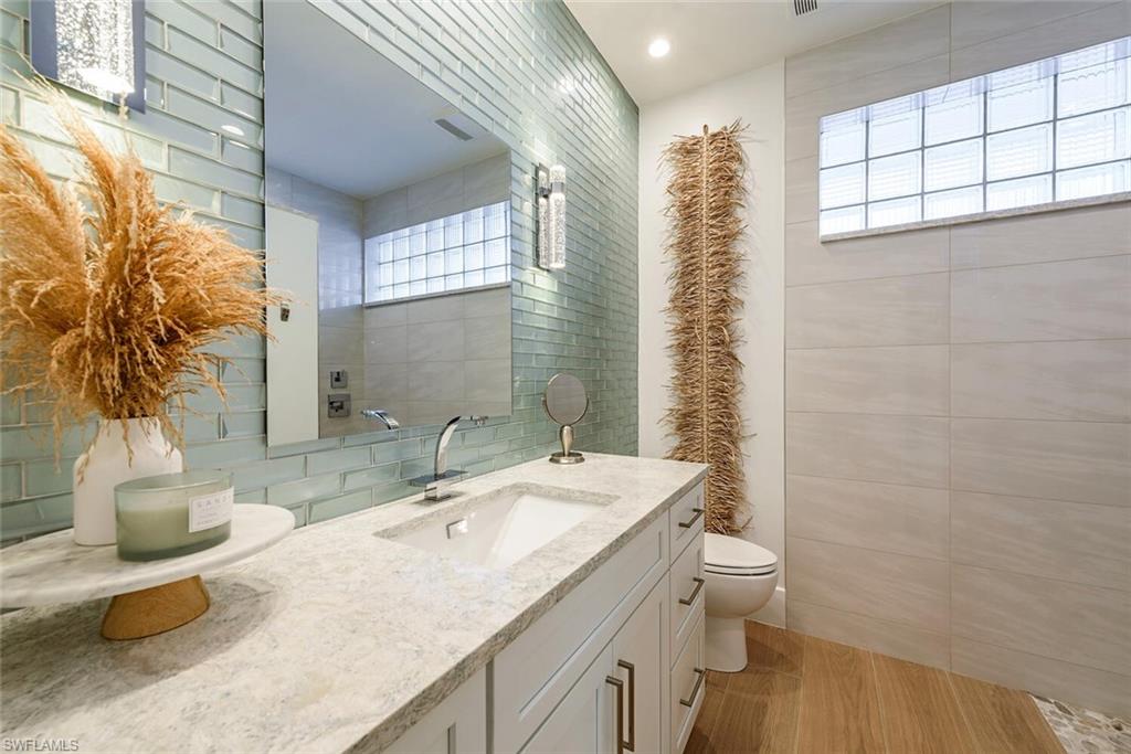 452 Willet Avenue Naples, FL 34108 - Photo 13 of 28 a bathroom with a granite countertop sink mirror vanity and toilet