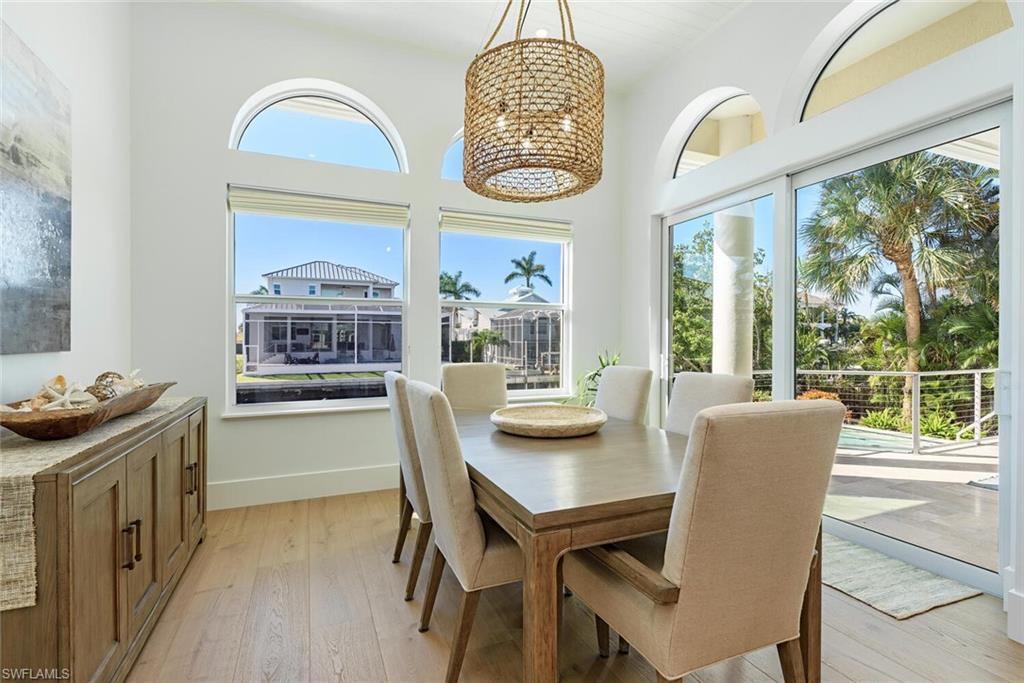 452 Willet Avenue Naples, FL 34108 - Photo 8 of 28 a dining room with furniture a chandelier and wooden floor