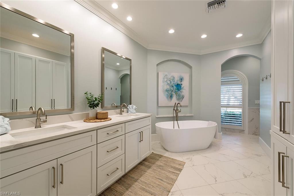 452 Willet Avenue Naples, FL 34108 - Photo 10 of 28 a spacious bathroom with a double vanity sink a mirror and a bathtub