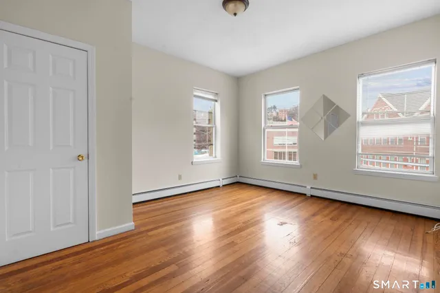 an empty room with wooden floor and windows