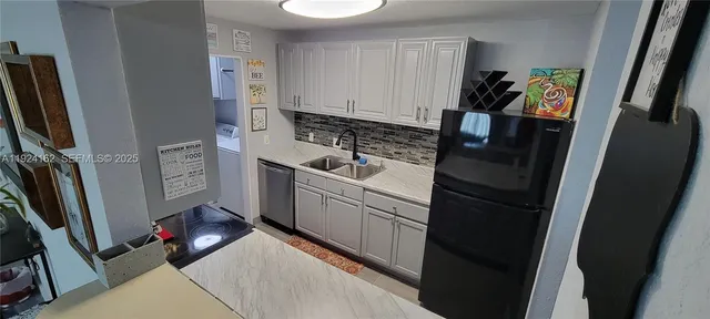 a kitchen with kitchen island a stove and a refrigerator with white cabinets