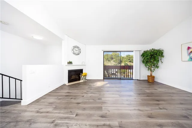 a view of a livingroom with wooden floor a fireplace and windows