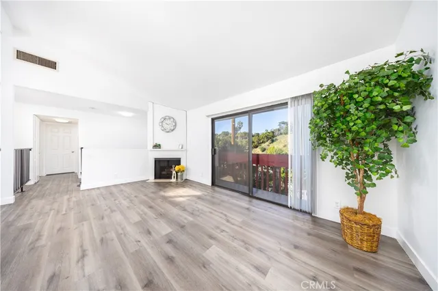 a view of empty room with wooden floor and plant