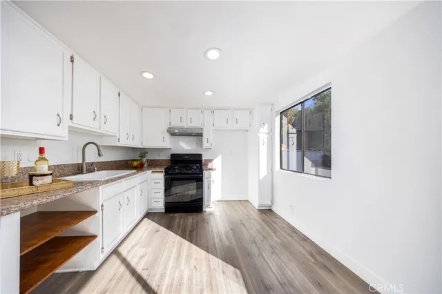 a kitchen with granite countertop a stove a sink and a refrigerator
