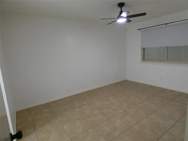 a view of an empty room and chandelier fan