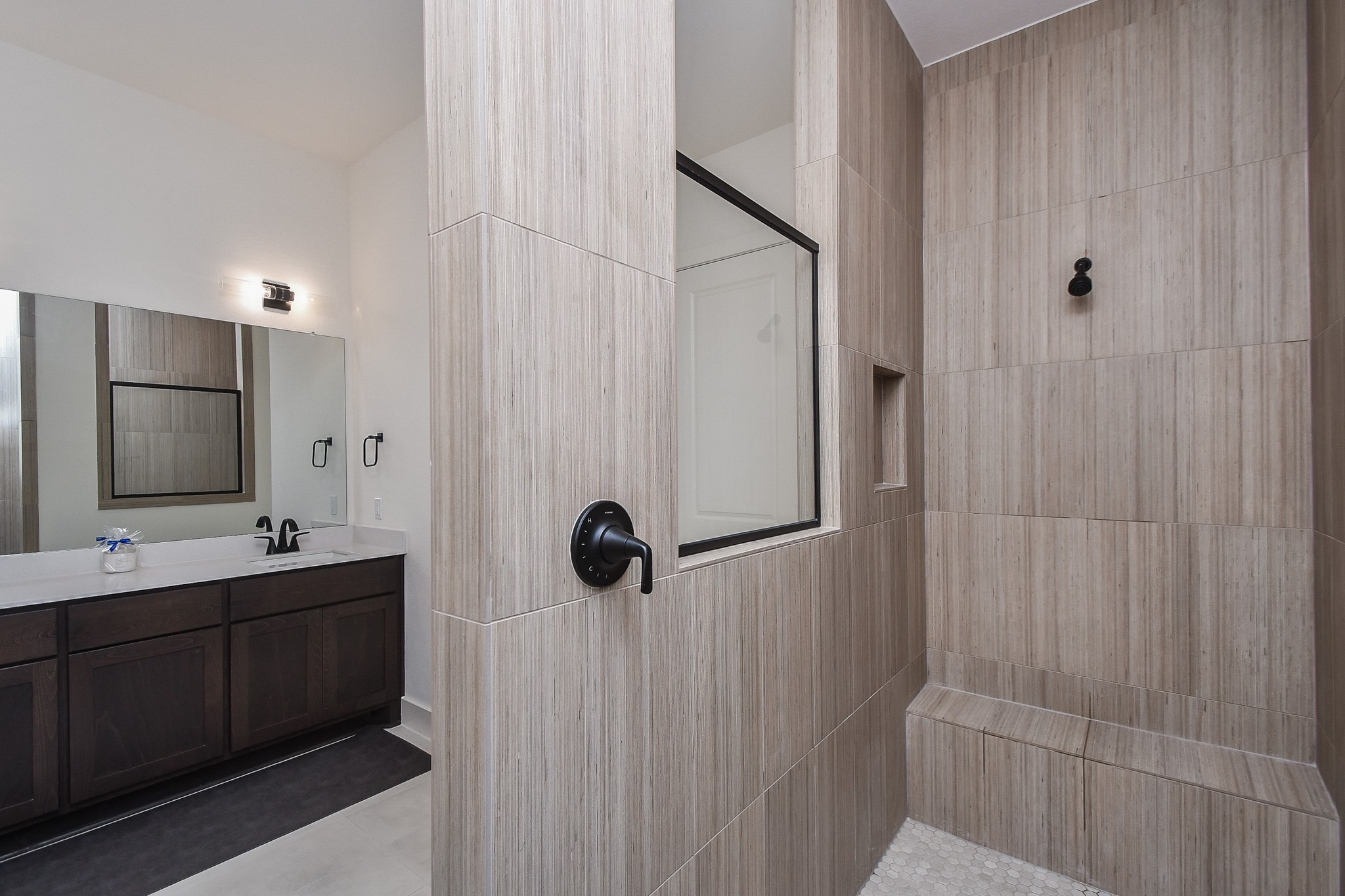 31915 Sky Rdg Lane Fulshear, TX 77441 - Photo 28 of 38 Discover the elegance of this primary bathroom, featuring a sleek, spacious shower with modern tilework and a sophisticated vanity with dark wood cabinetry, perfect for a luxurious retreat.