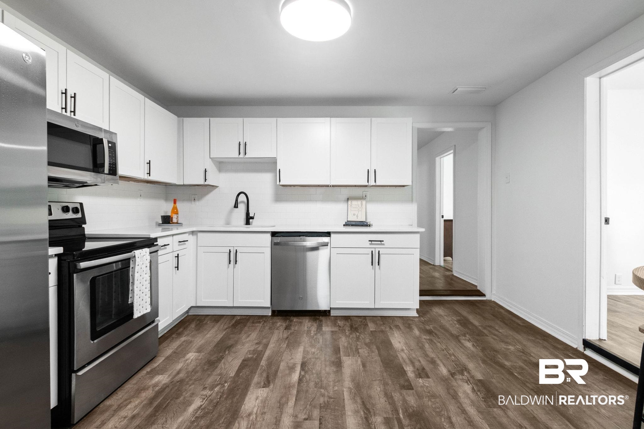 128 Bush Avenue Mobile, AL 36604 - Photo 11 of 40 Kitchen with white cabinetry, stainless steel appliances, dark wood-style flooring, and decorative backsplash