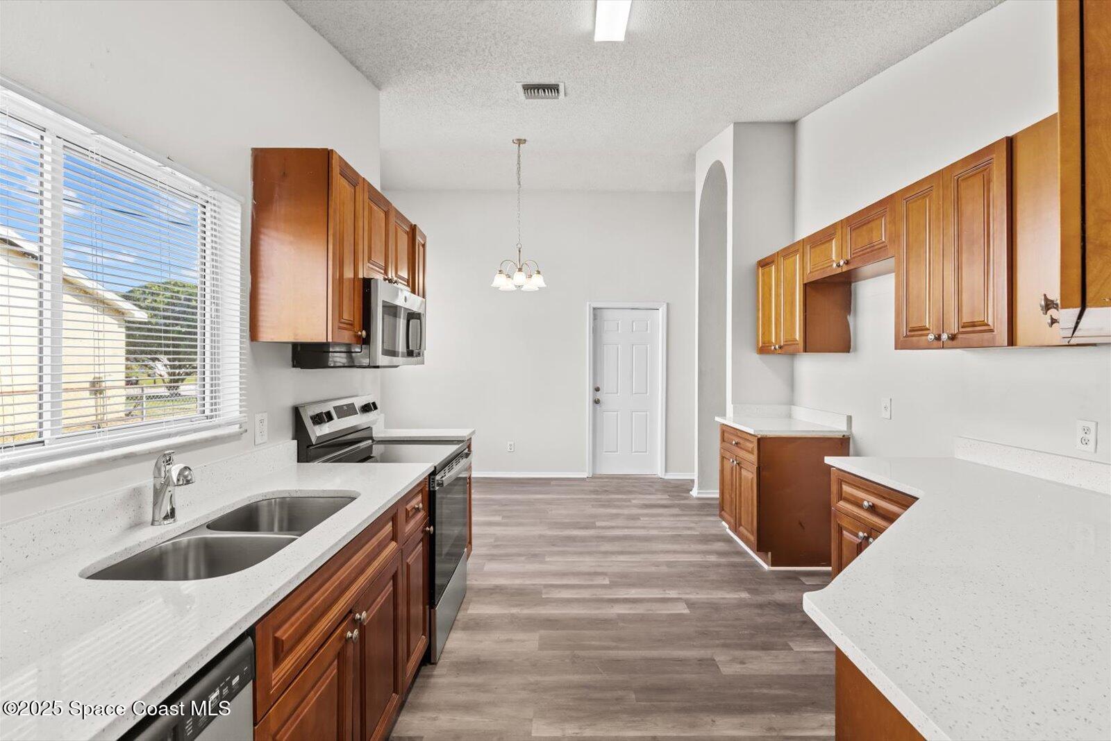 1037 Southwest California Boulevard Port St. Lucie, FL 34953 - Photo 11 of 38 a kitchen with wooden cabinets a sink a stove and a window