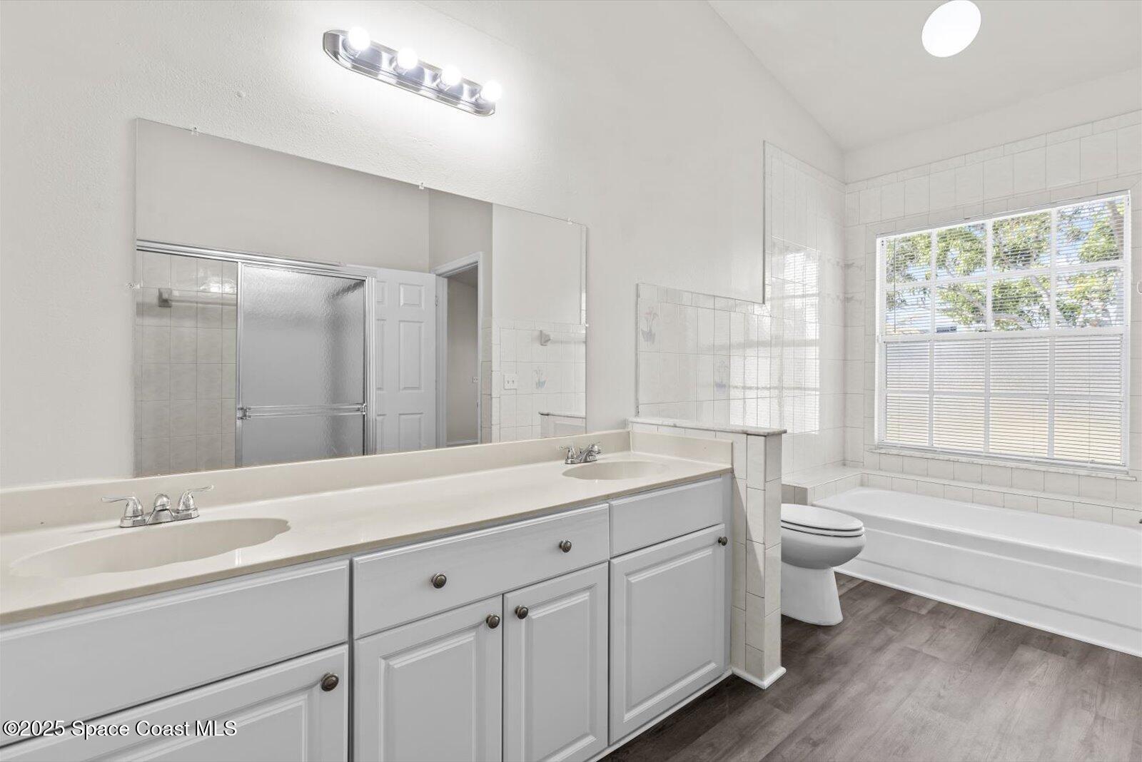 1037 Southwest California Boulevard Port St. Lucie, FL 34953 - Photo 19 of 38 a bathroom with a double vanity sink toilet a large mirror and shower