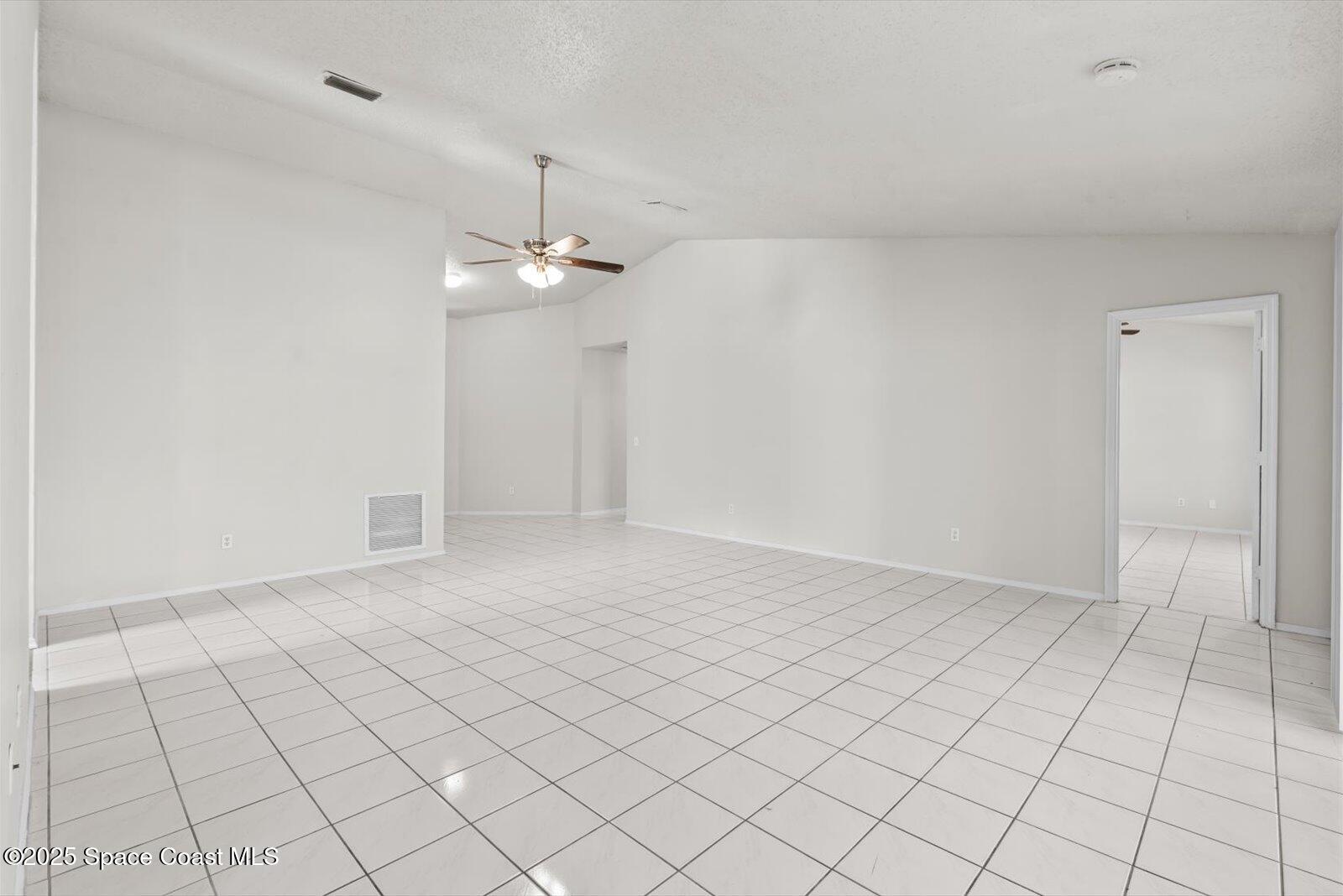 1037 Southwest California Boulevard Port St. Lucie, FL 34953 - Photo 7 of 38 an empty room with white walls and chandelier fan