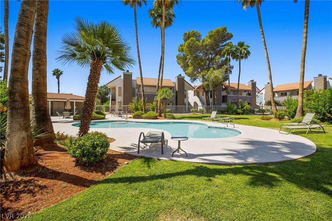 3311 Sunfish Drive, Unit D Henderson, NV 89014 - Photo 18 of 21 A tranquil community pool, embraced by vibrant landscaping and mature palm trees, awaits your relaxation.