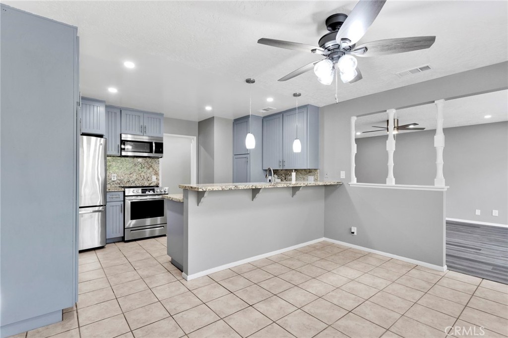 15846 Inyo Street Victorville, CA 92395 - Photo 12 of 44 a kitchen with granite countertop a refrigerator and a stove top oven