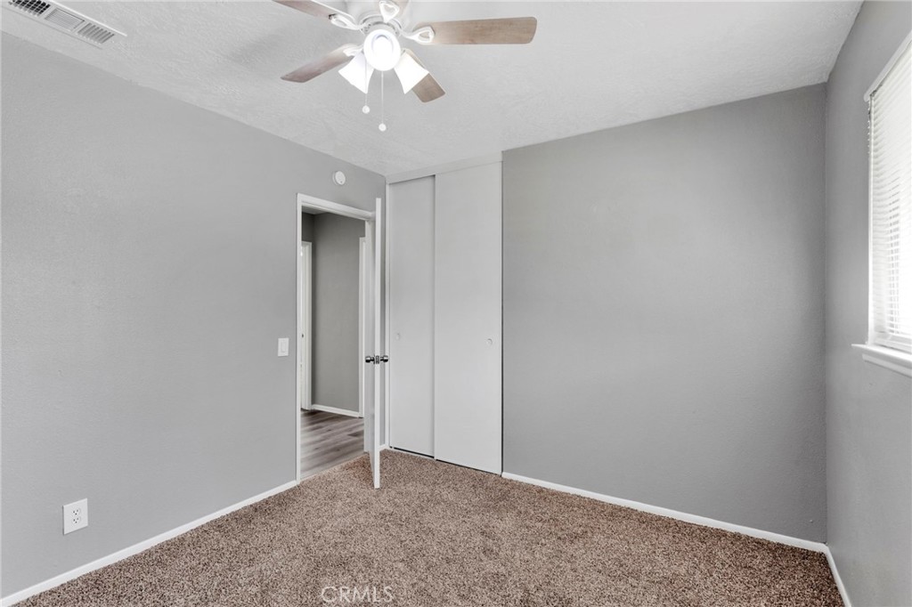 15846 Inyo Street Victorville, CA 92395 - Photo 24 of 44 an empty room with a chandelier fan and windows