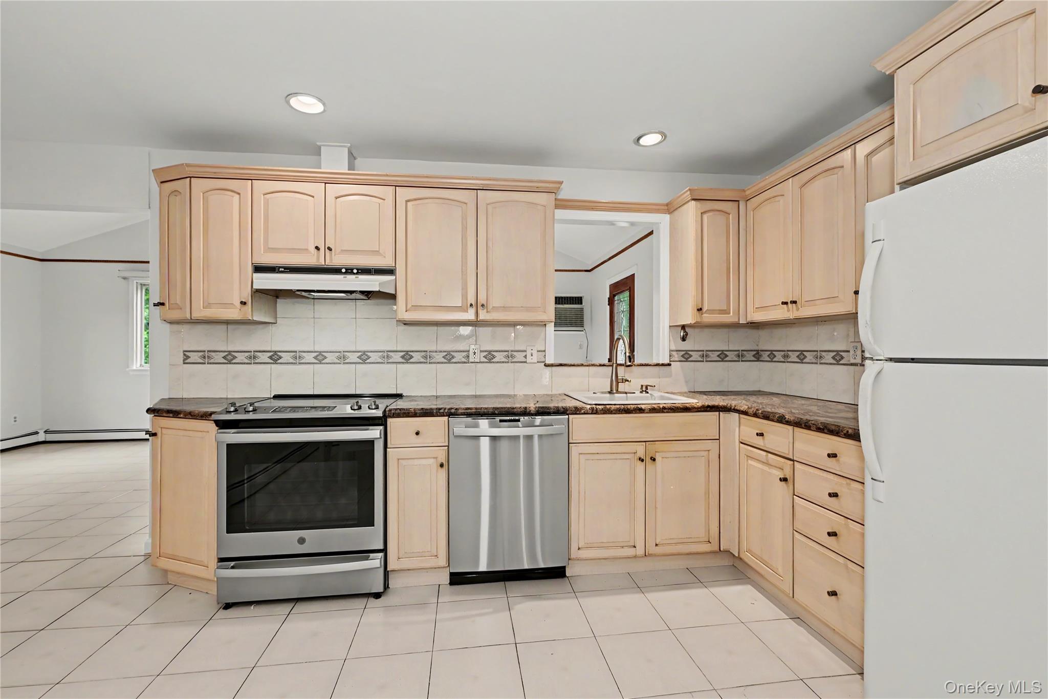 568 Manville Road, Unit UPPER R Pleasantville, NY 10570 - Photo 11 of 32 Kitchen featuring light wood cabinetry, stainless steel range, stainless steel dishwasher, tile flooring, and granite countertops. The pass through goes into the family room.