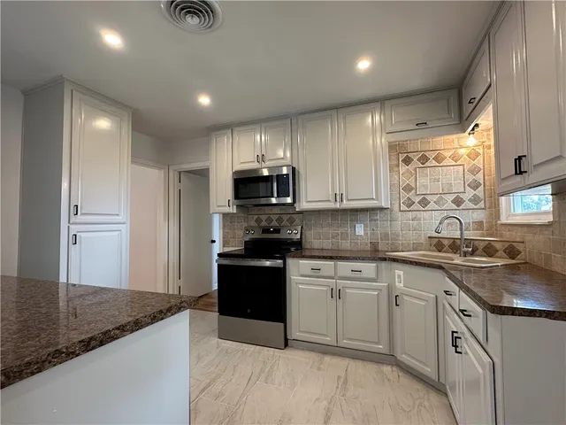 a kitchen with kitchen island granite countertop a sink appliances cabinets and counter space
