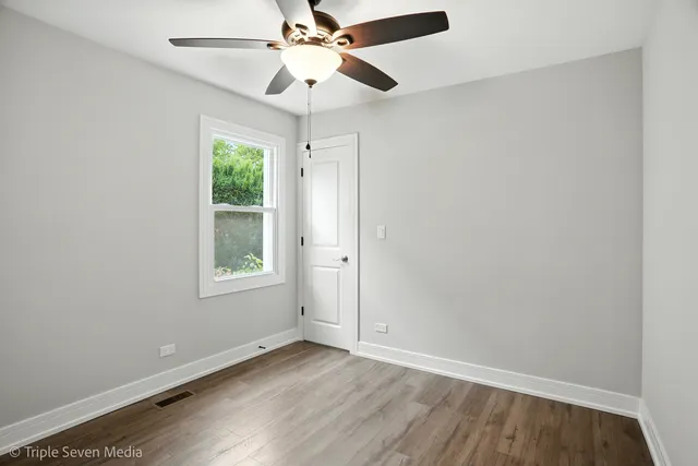 an empty room with a window and a fan