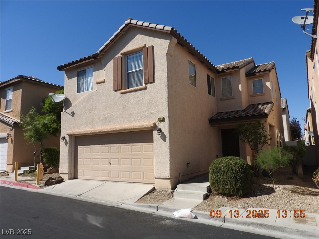 Mediterranean / spanish home with a tile roof, stucco siding, and an attached garage