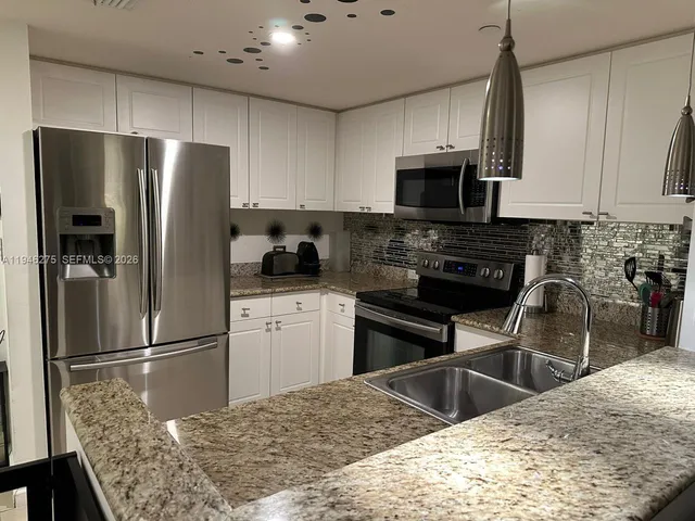 a kitchen with stainless steel appliances granite countertop a refrigerator a stove a sink a microwave and a refrigerator