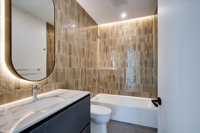 a bathroom with a granite countertop sink a toilet and shower