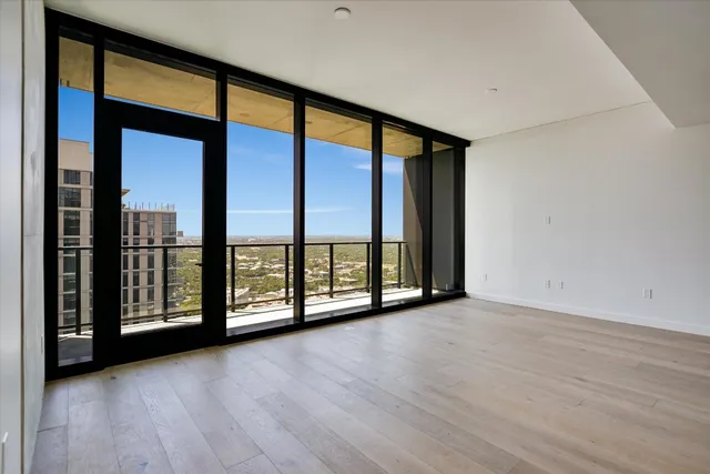 an empty room with wooden floor and windows with balcony