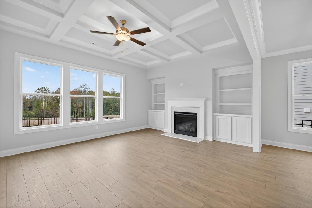 5579 Spring Street Flowery Branch, GA 30542 - Photo 14 of 65 an empty room with windows a fireplace a ceiling fan and wooden floor
