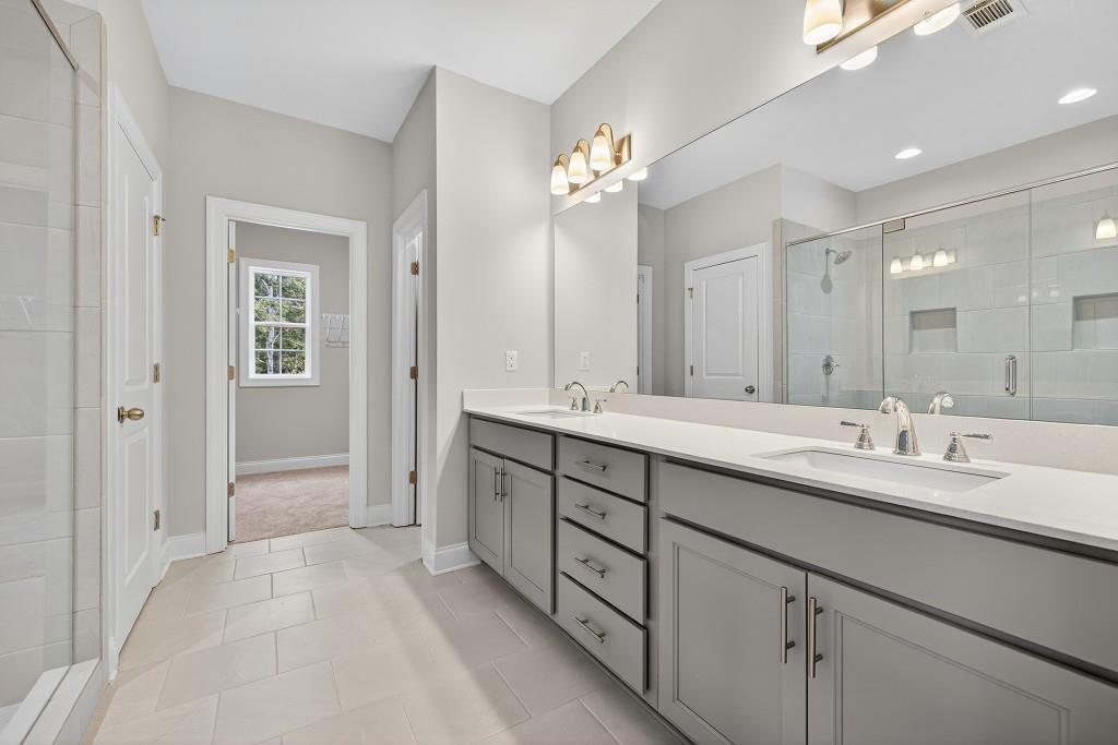 5579 Spring Street Flowery Branch, GA 30542 - Photo 28 of 65 a spacious bathroom with a granite countertop sink a mirror and a shower