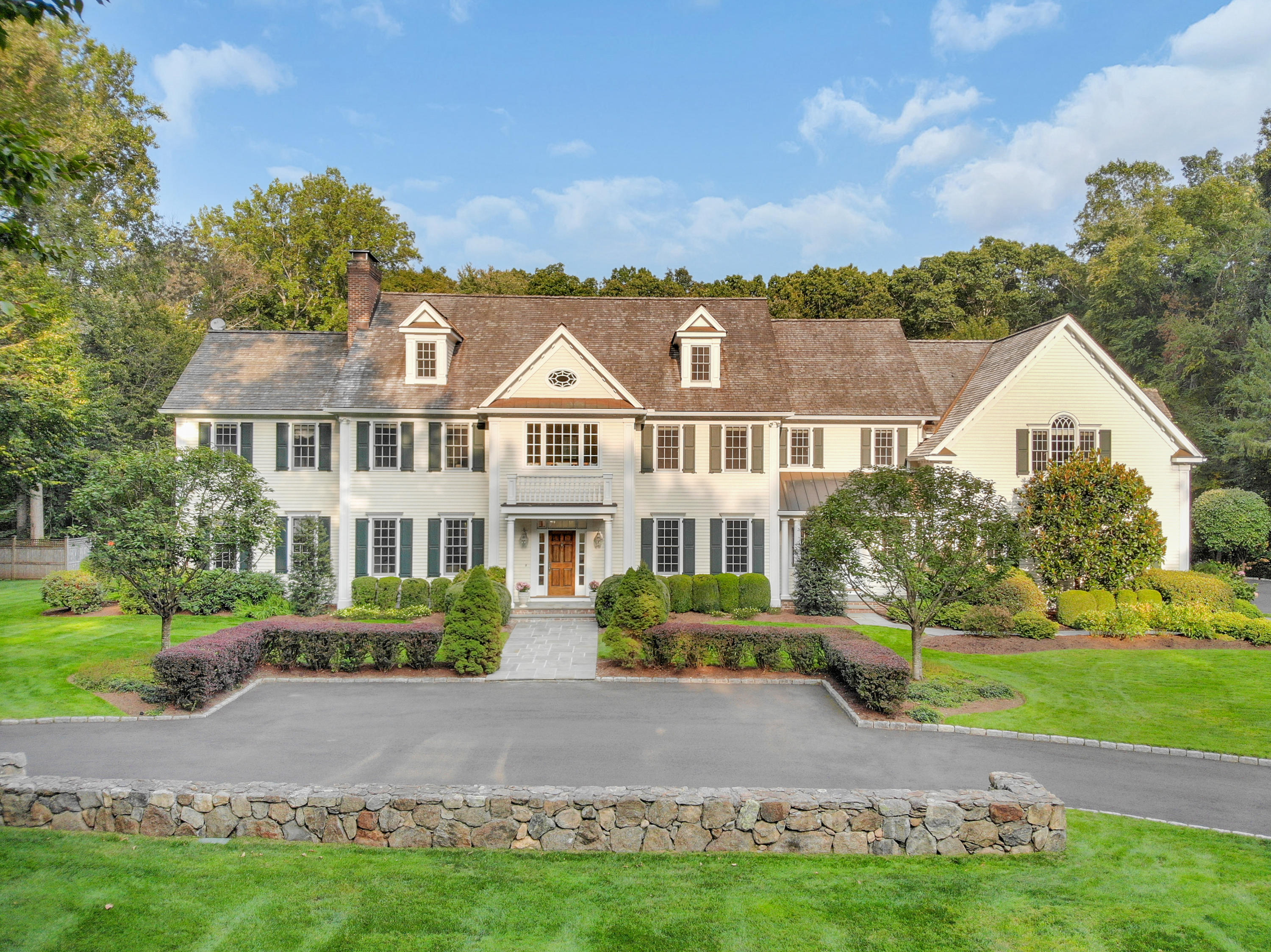 a view of a white house next to a yard with big trees