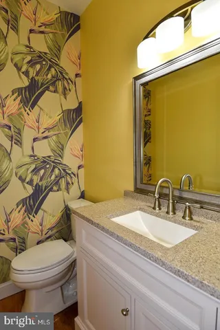 a bathroom with a granite countertop toilet sink and mirror