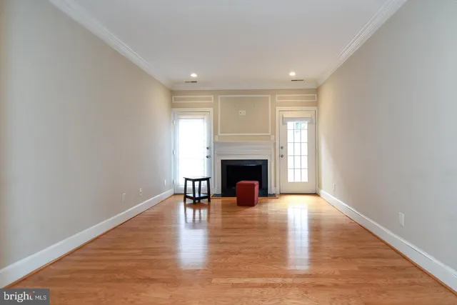 a view of an empty room with wooden floor fireplace and a window