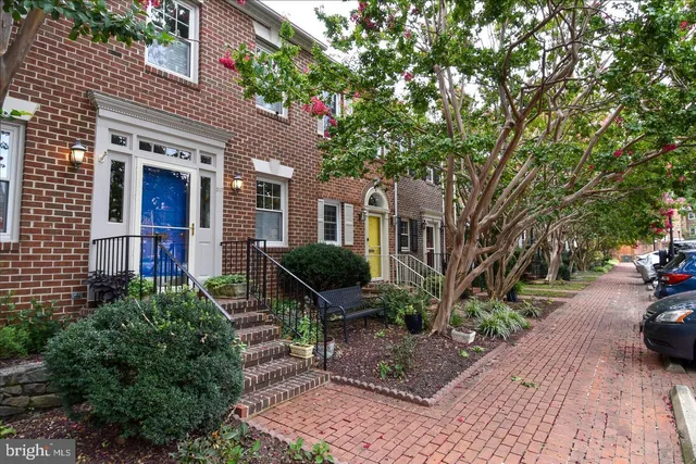 a view of a brick house with many windows next to a yard