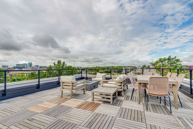 a roof deck with couches and potted plants with sky view