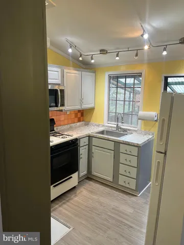 a kitchen with granite countertop a sink cabinets and stainless steel appliances