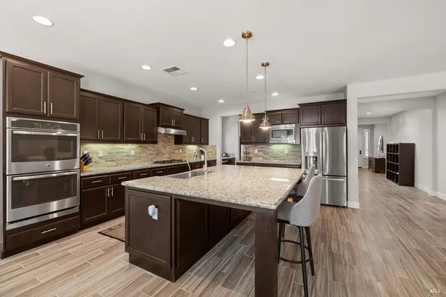 a kitchen with stainless steel appliances granite countertop a refrigerator a stove and a wooden floors