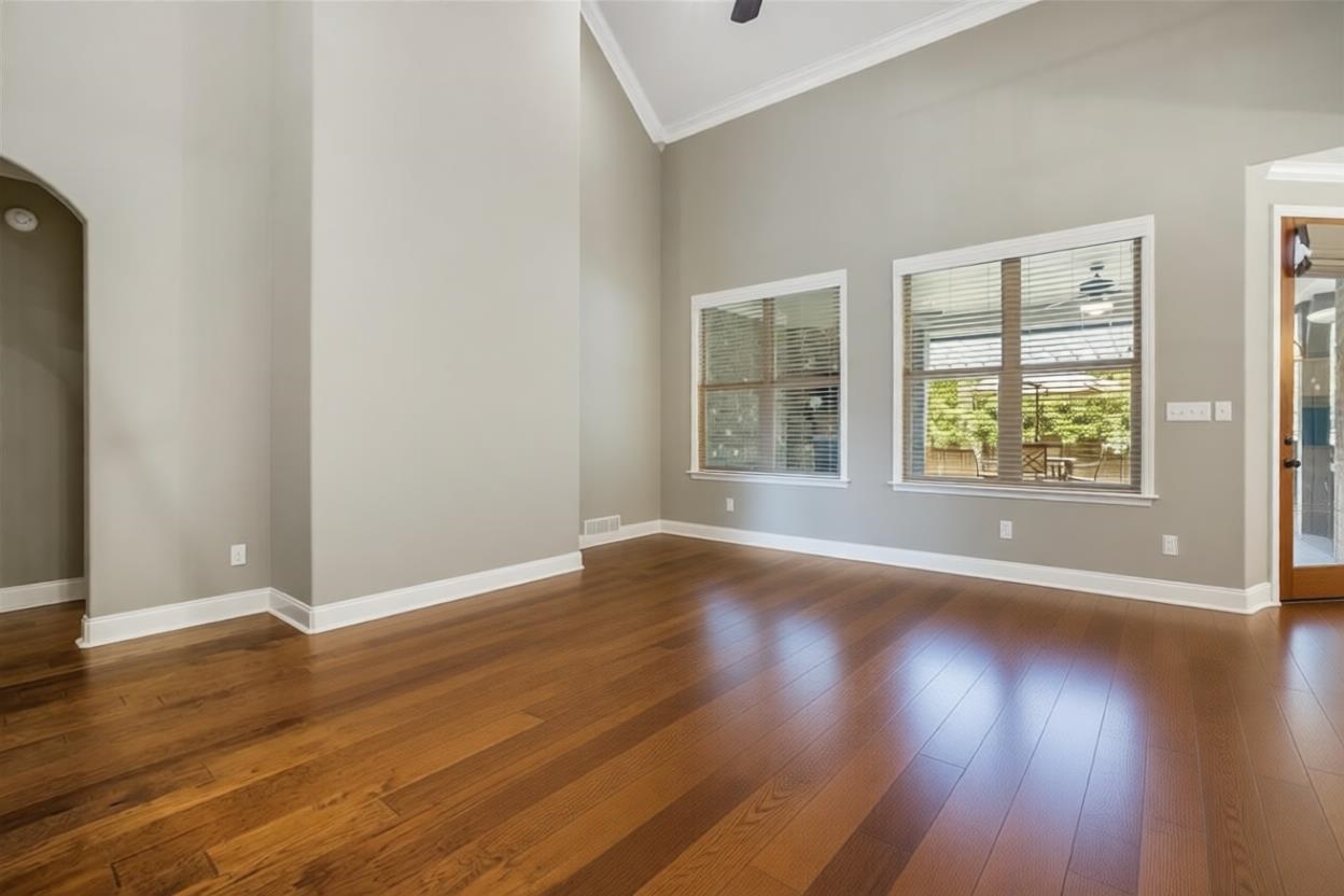 1357 Carmony Street Collierville, TN 38017 - Photo 6 of 16 Empty room with a towering ceiling, dark wood-style floors, ornamental molding, arched walkways, and ceiling fan